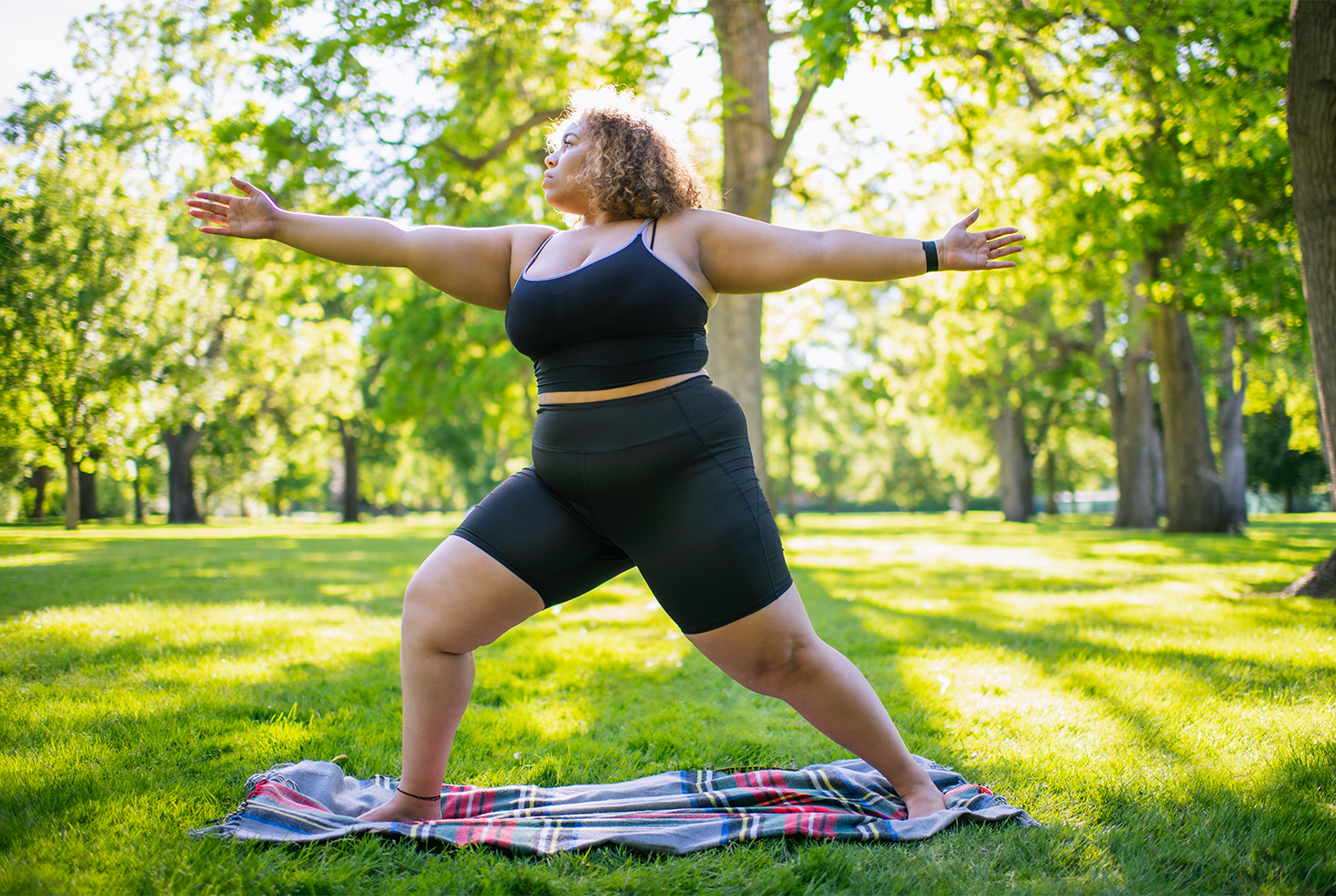 Une femme en surpoids pratiquant du yoga dans un parc. Une activité physique à faible impact pour le périnée et permettant de lutter contre la surcharge pondérale. 