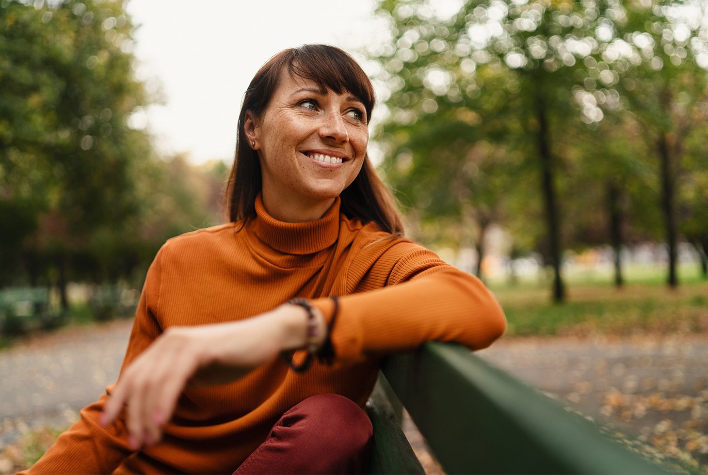 Portrait d’une jeune femme assise sur un banc public, l’air souriant