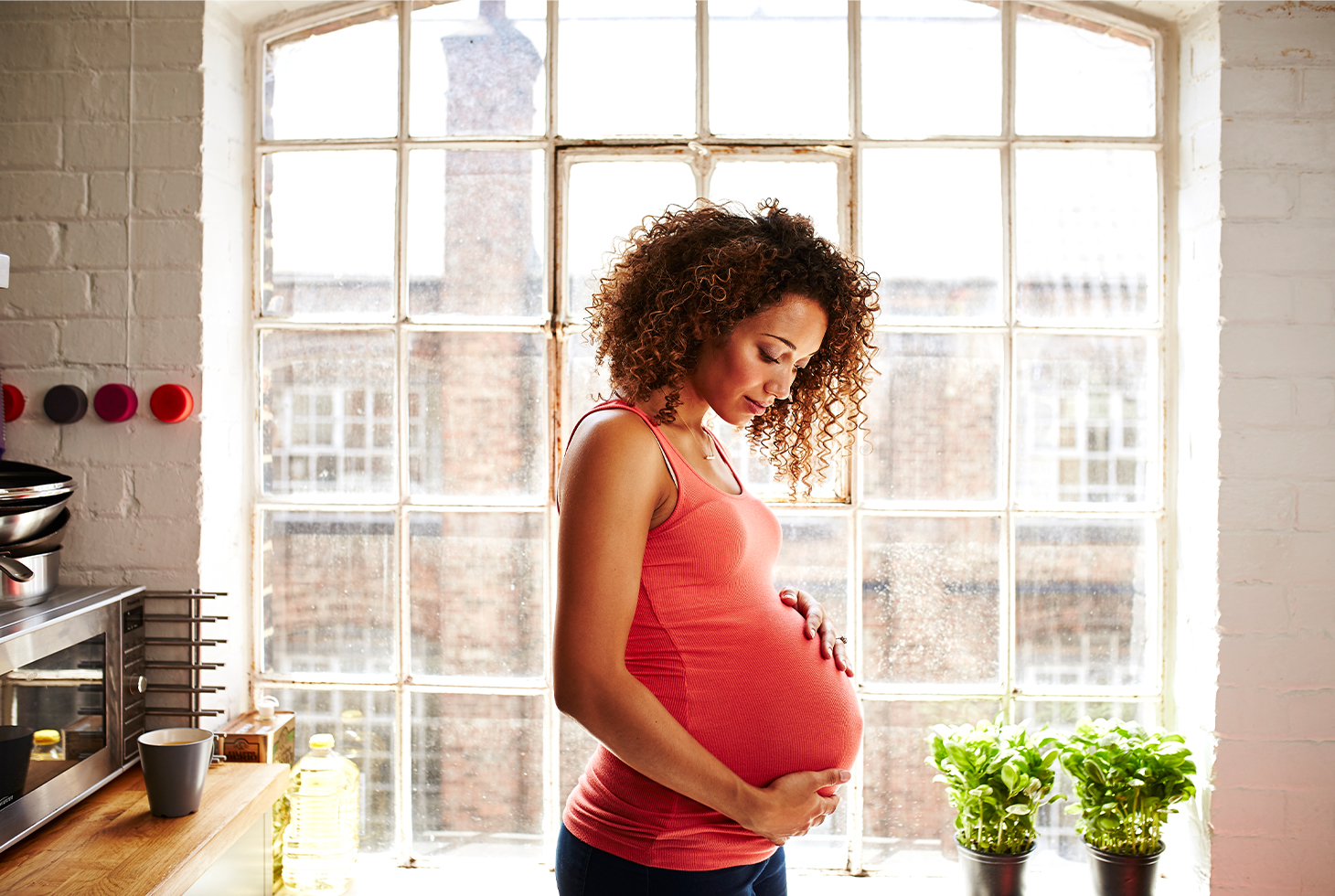 Portrait d’une femme enceinte les mains posées sur son ventre. Visuel d’illustration pour la thématique de l’incontinence liée à la grossesse.