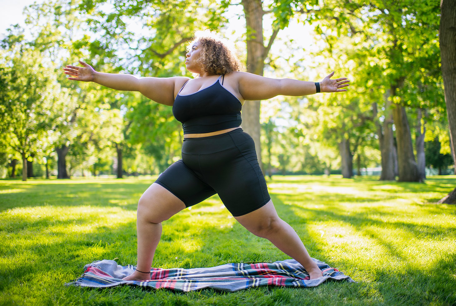 Une femme en surpoids pratiquant du yoga dans un parc. Une activité physique à faible impact pour le périnée et permettant de lutter contre la surcharge pondérale.