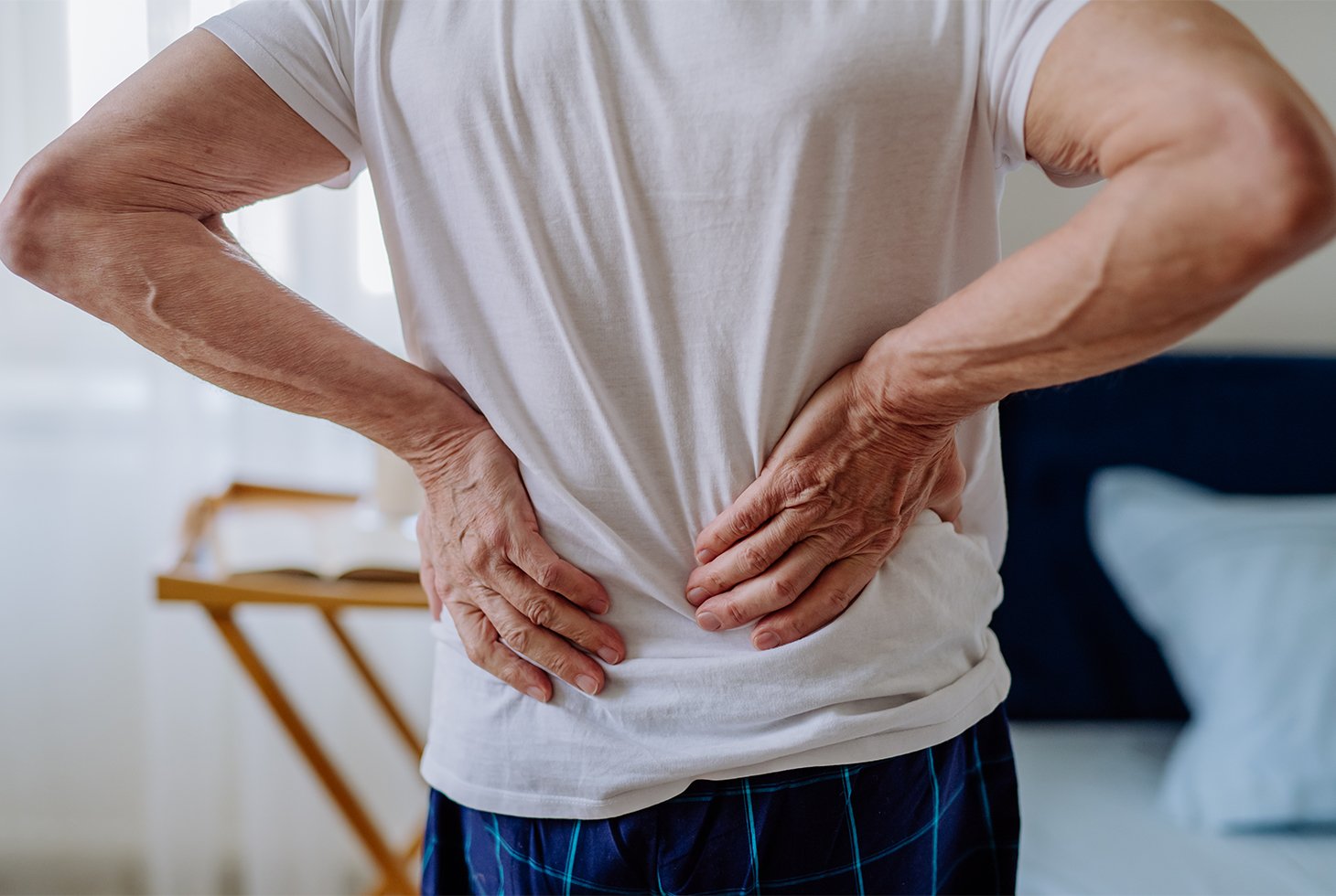Vue de dos d’un homme se tenant le bas du dos. Visuel pour illustrer le risque de troubles musculo-squelettiques chez les aidants.