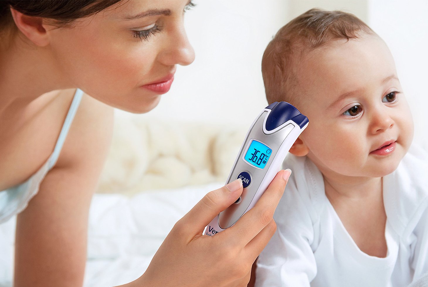 Une femme utilisant le thermomètre infrarouge Veroval® baby pour mesurer la température corporelle de son enfant. Cet appareil est préconisé pour une mesure de la température au niveau du front.